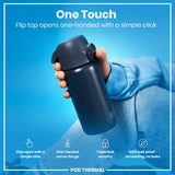 A dark-grey insulated water bottle is held in a hand. Its flip top opens with a single click. The background is light blue.