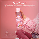 A pink unicorn-decorated water bottle is held; its flip top opens one-handed. The bottle features a triple lock security mechanism and is 100% leak-proof; the context is a pink background. The bottle is described as