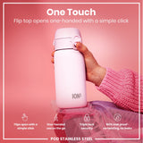 A pink ION8 stainless steel water bottle is being held; its flip top opens one-handed. The bottle rests on pink fabric against a pink background.