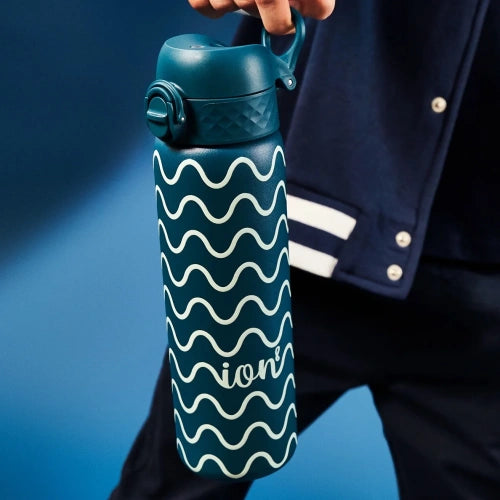 A teal water bottle, featuring a wavy pattern, is being held against a dark-blue backdrop. The bottle's brand name, "ALO," is subtly visible on its side.