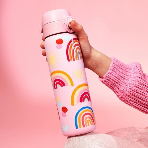 A pink water bottle, adorned with rainbow and sun designs, is being held by a person against a pink background.