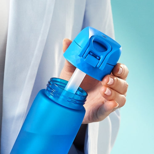 A blue water bottle has a blue cap with a straw being inserted by a person wearing a white robe.